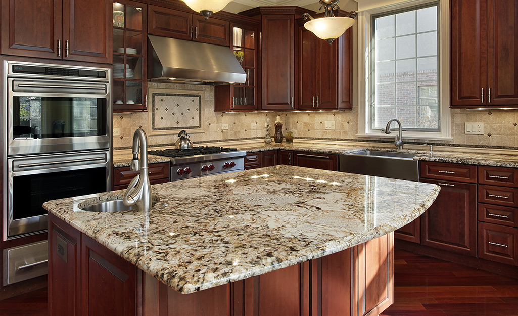 A kitchen island with brown granite countertops.