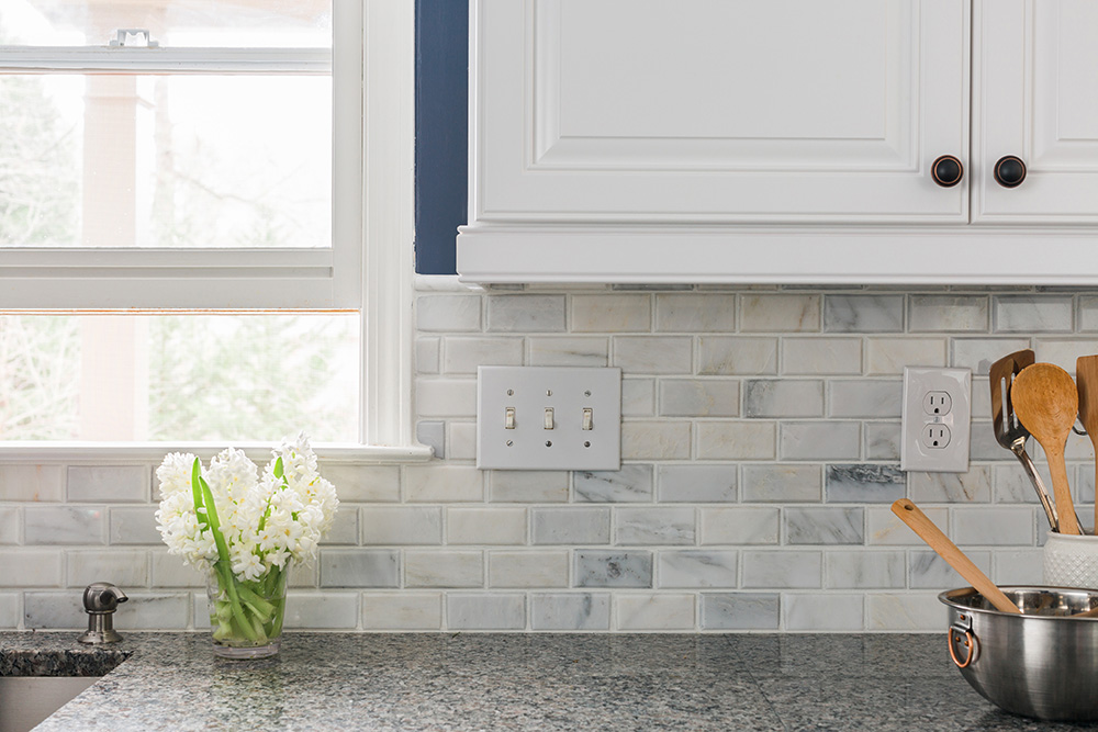 An updated kitchen backsplash over granite countertops.