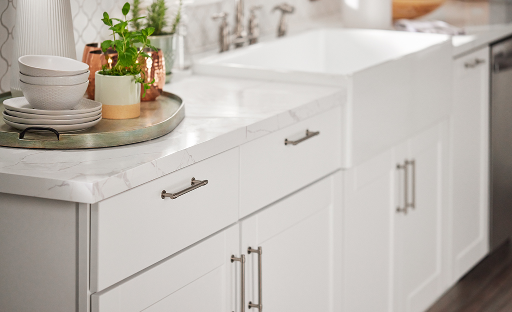 Marble countertops installed on top of white cabinets.