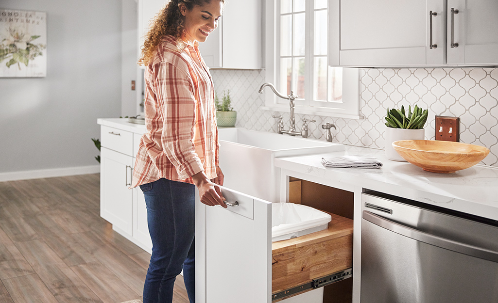 An open kitchen drawer holding two trashcans.