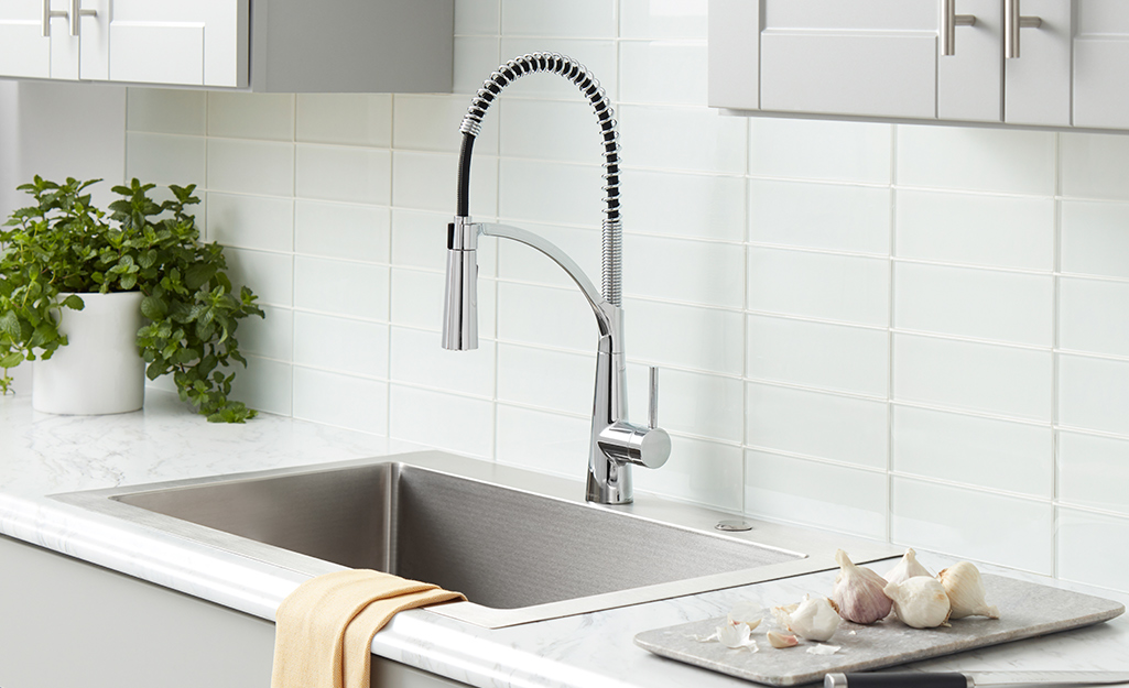 A new kitchen faucet with a flexible neck installed over a sink.