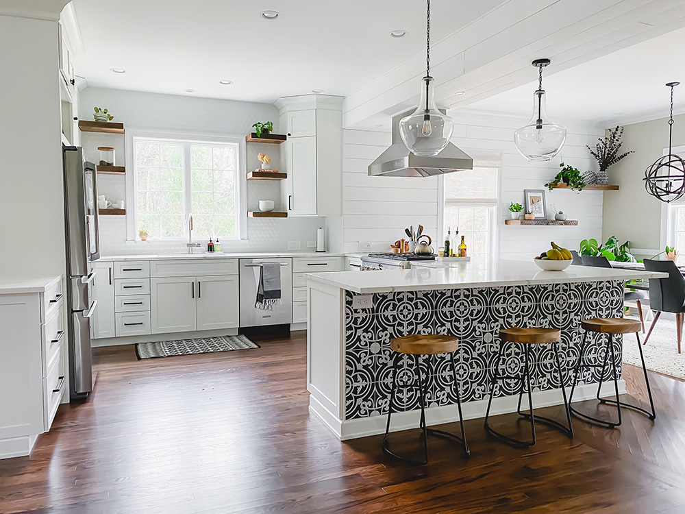 An updated white kitchen with open shelving and a decorative tile bar area.