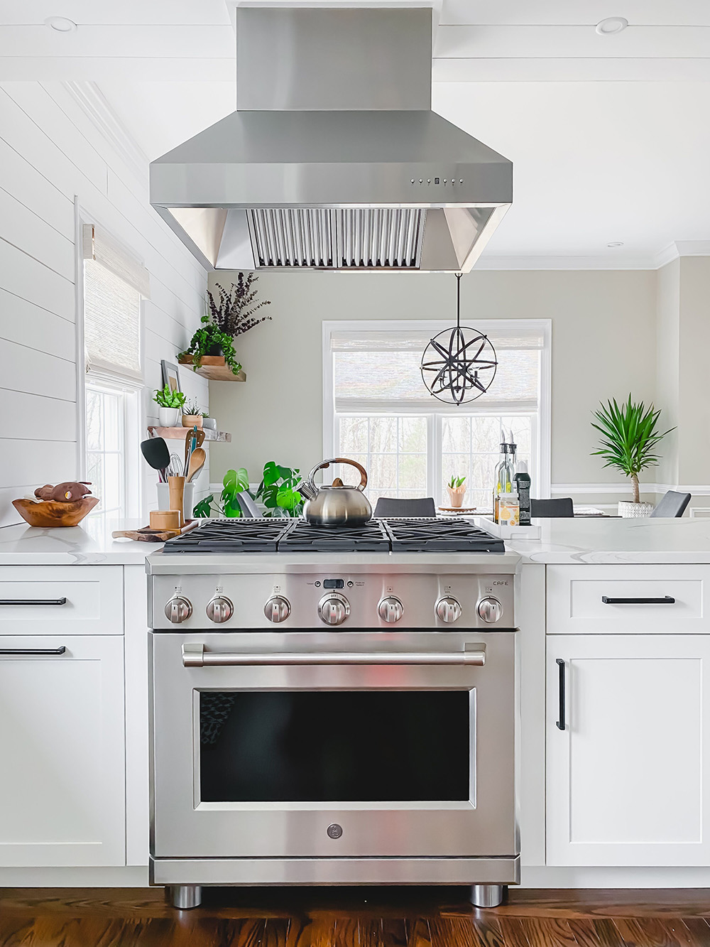 An open kitchen with a vent hood hanging over a gas oven.