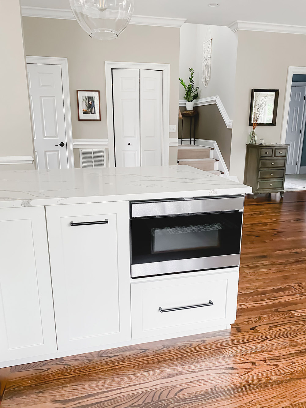 A white kitchen with a stainless steel drawer microwave.