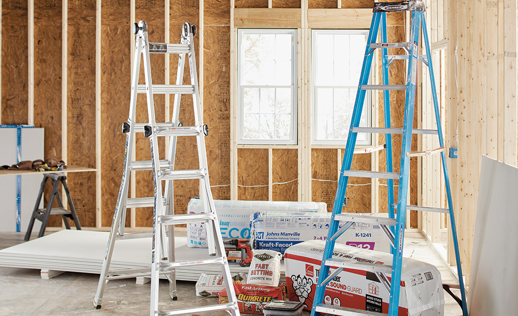 Two different ladders in an unfinished room