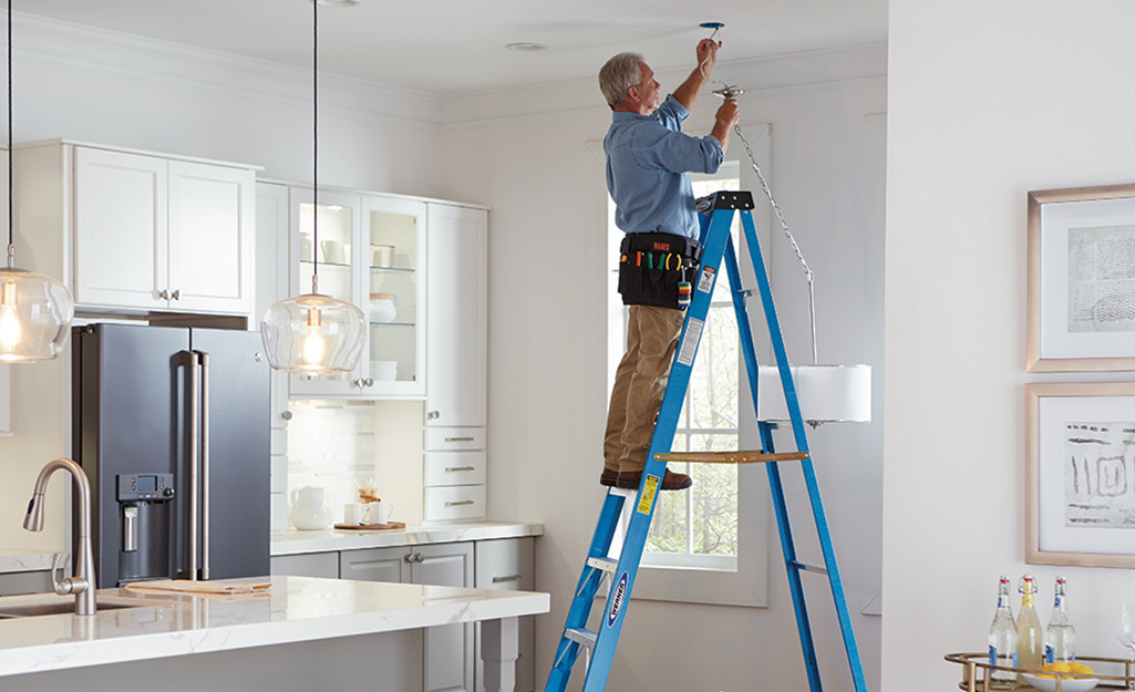 A man using a ladder to change a bulb.