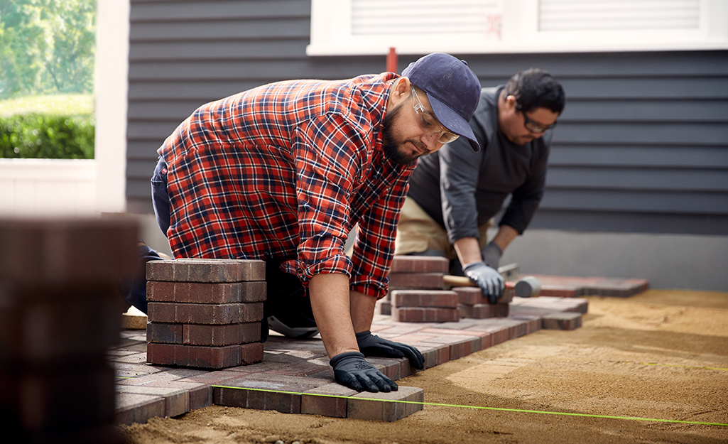 A homeowner laying down a a brick patio. A homeowner laying down a a brick patio.