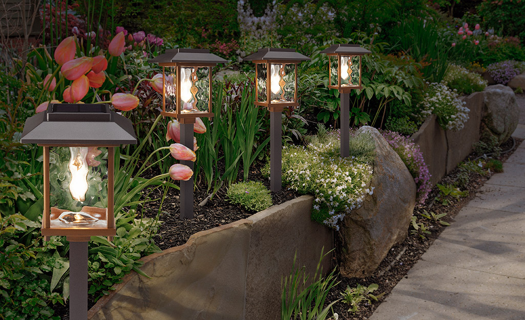 A garden path lined with lantern walkway lights. A garden path lined with lantern walkway lights.