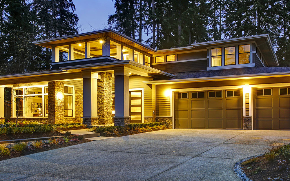 The exterior of a house that is illuminated with flood lights and other landscape lighting.