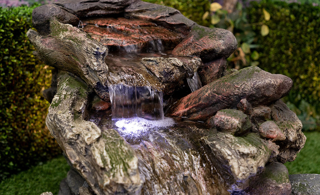 An outdoor water fountain with a lit waterfall feature.