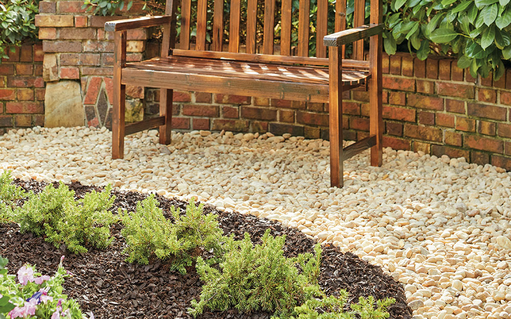 Crushed pebble path under a wood garden bench