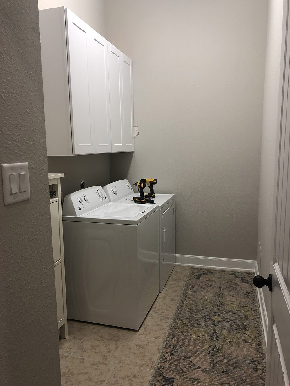 A pair of white cabinets mounted on a wall above a washer and dryer.