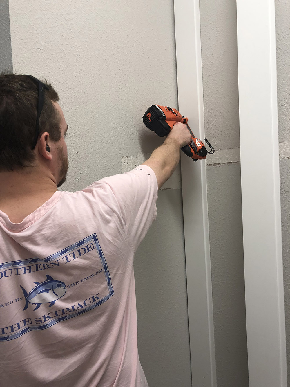 A man installing white vertical shiplap on a wall.