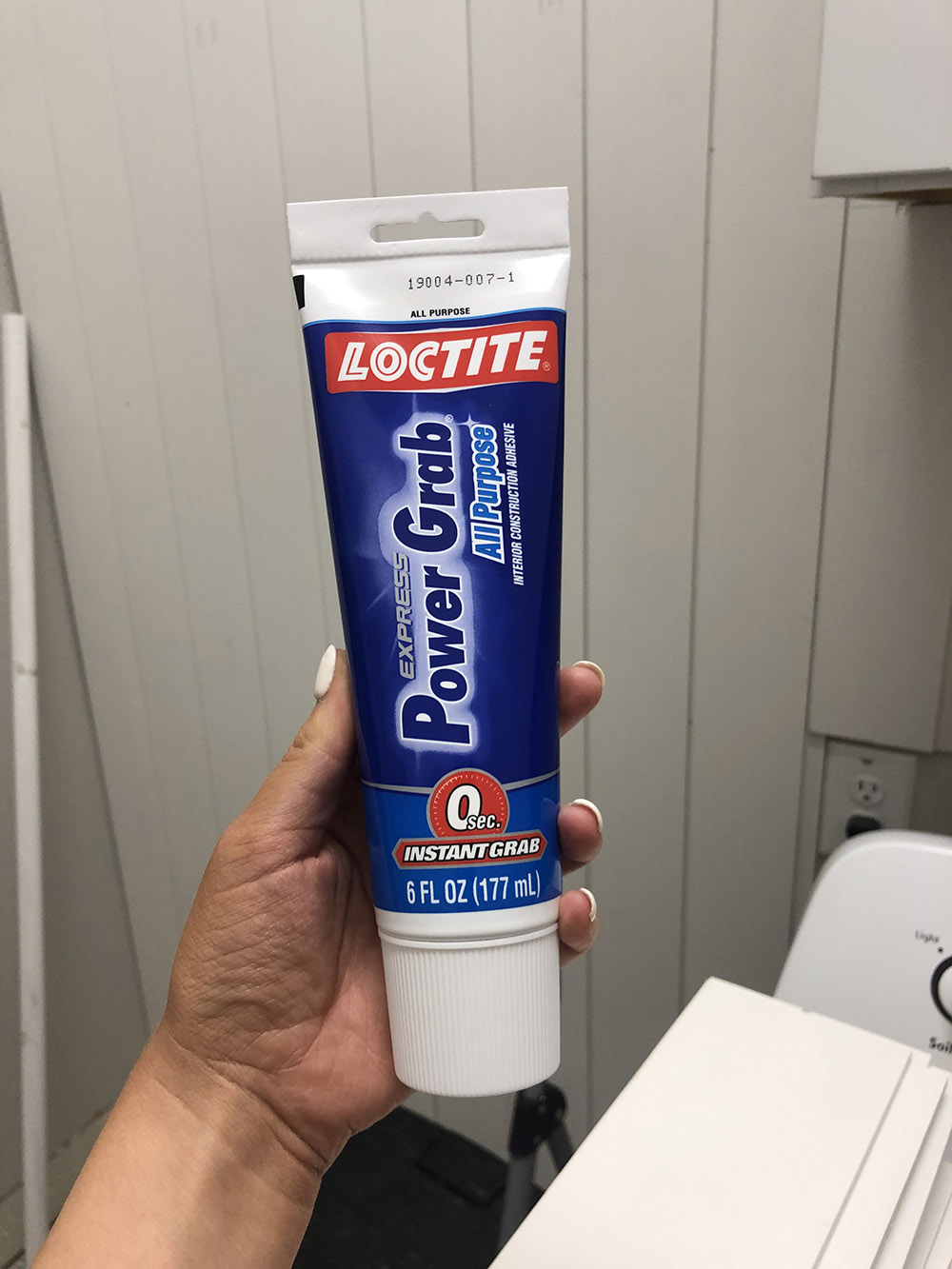 A person holding a tube of Loctite power grab.