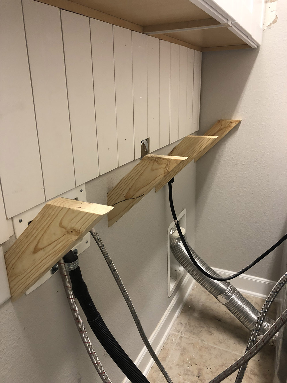 A laundry room wall with four angled wood supports sticking out.