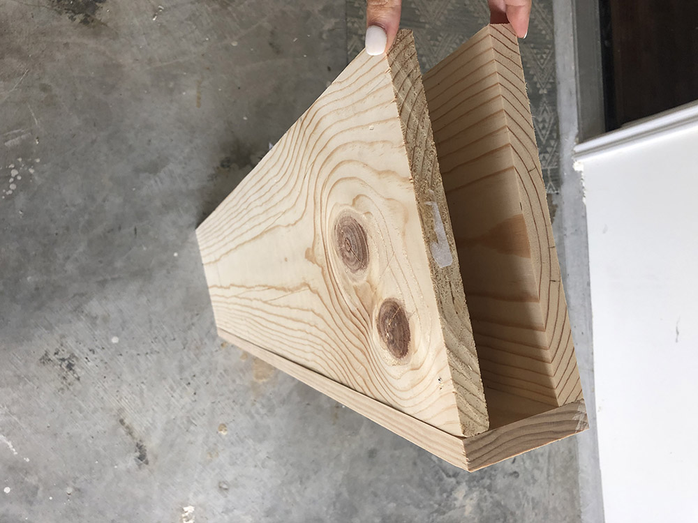 A person holds the sides of a DIY floating shelf with a hollow center.