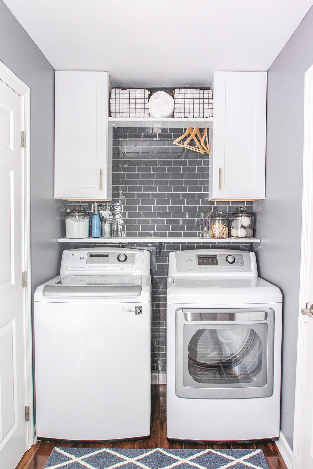 An updated laundry room with an accent wall of gray peel and stick wall tiles. 