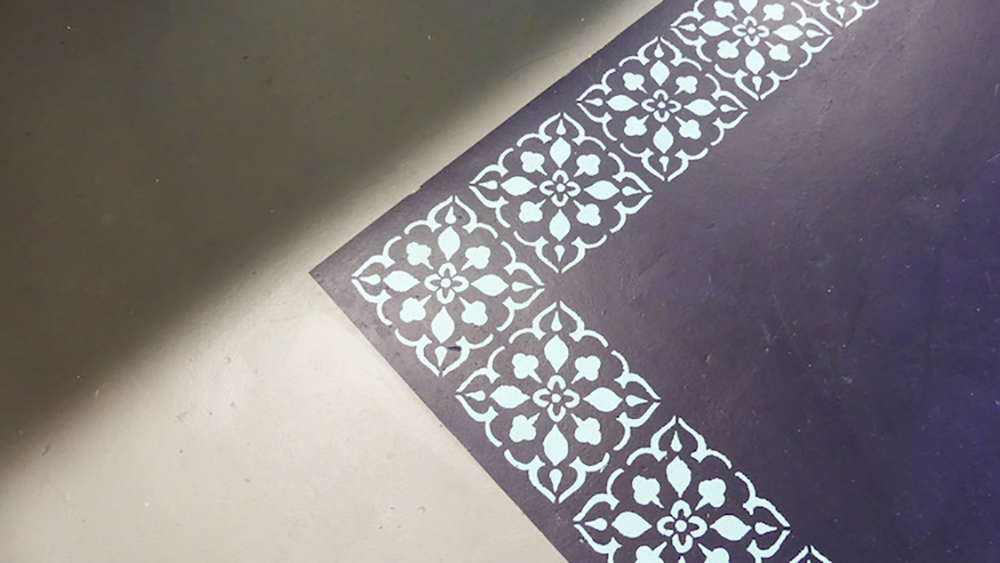 A laundry room floor with a painted stencil rug.