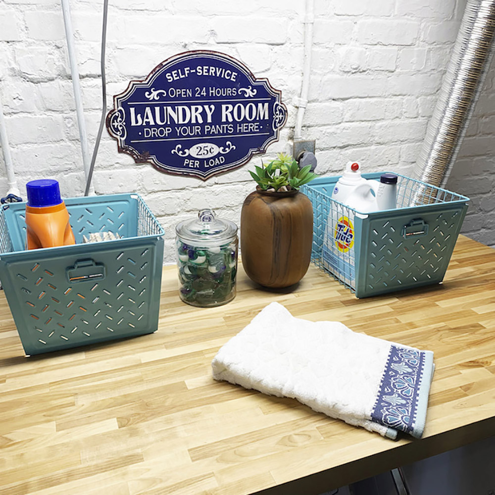 A pair of teal baskets filled with laundry supplies sit on a butcher block counter.