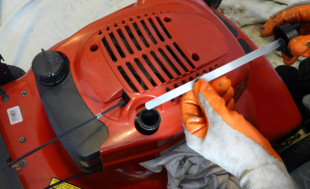 Someone changing oil in a lawn mower.