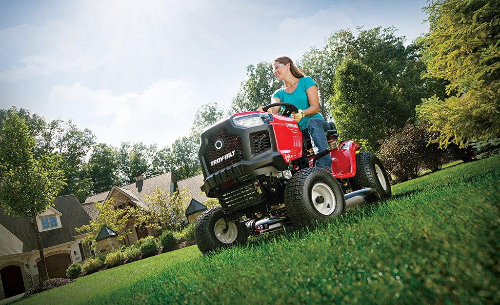 Woman cutting grass on a riding lawn mower.