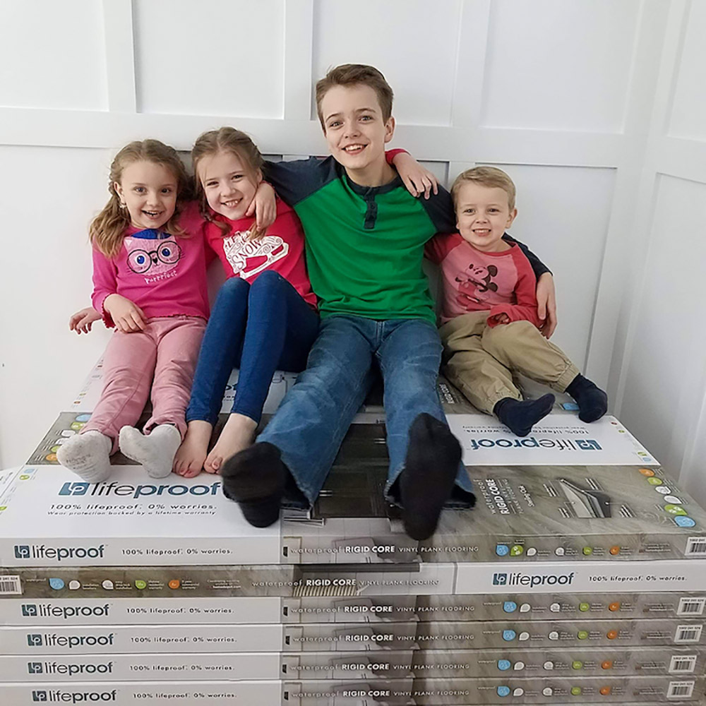 A family sitting on LifeProof flooring boxes