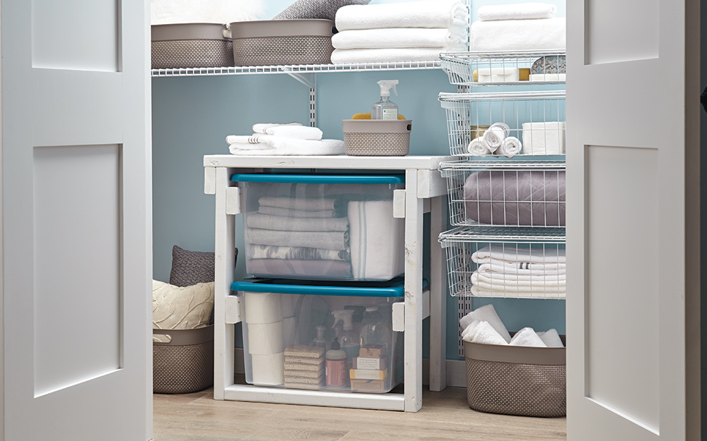 An organized linen closet with container storage and wire shelves