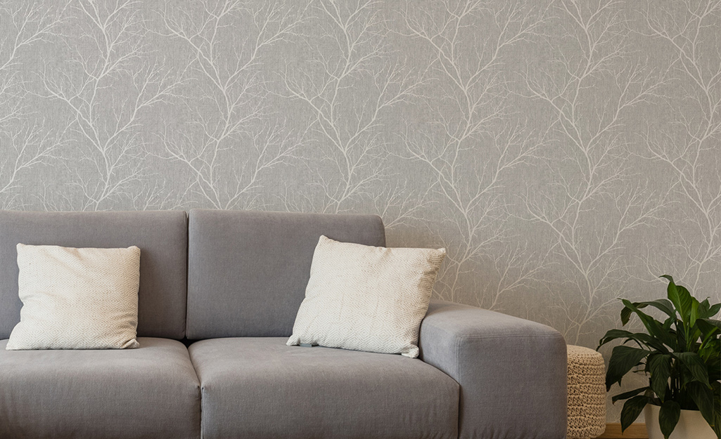 Grey wallpaper in a living room with a grey sofa.