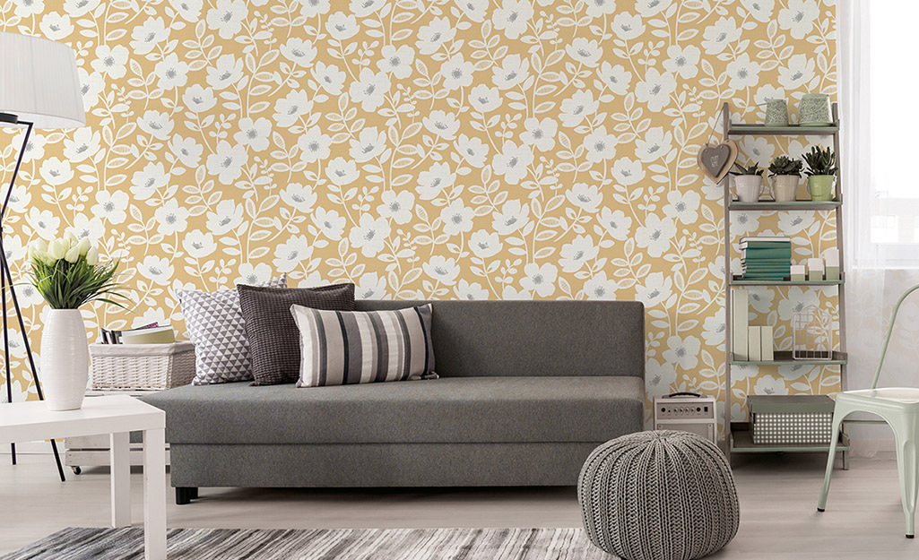 Yellow wallpaper in a living room with a grey sofa and other decor.