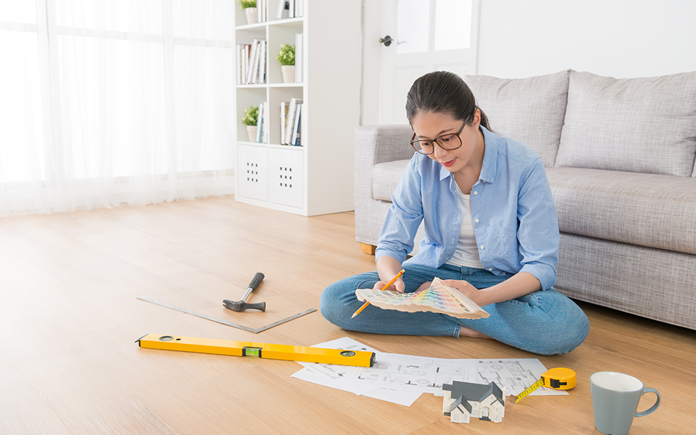 A woman sitting on the floor looking at a paint chip fan deck.