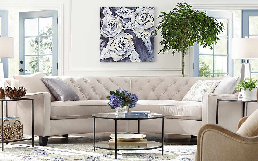 A living room with white sectional sofa and large framed art.