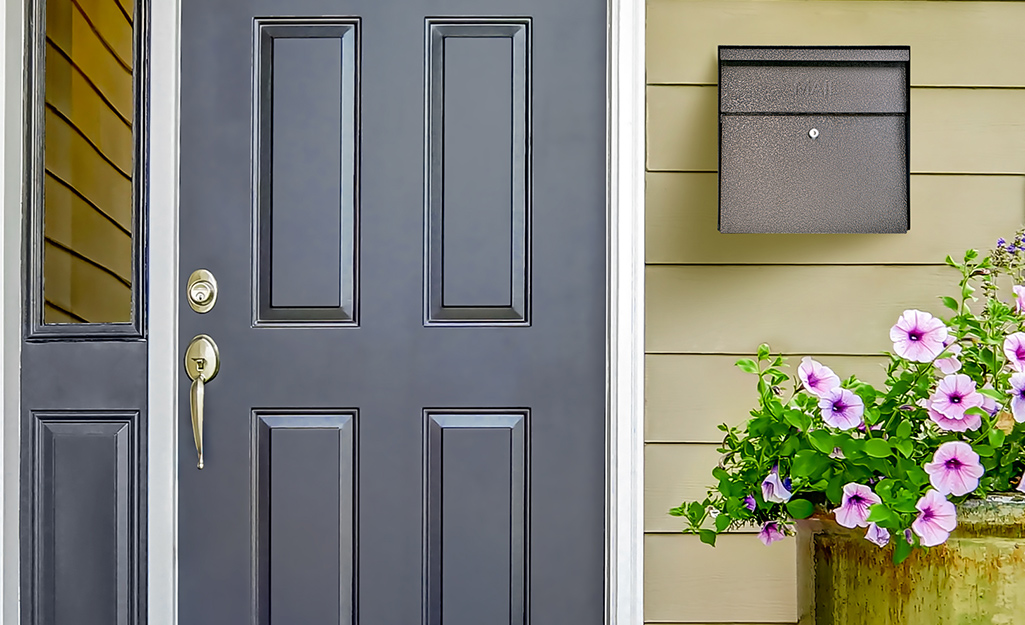 Flowers near a mailbox attached to a home.