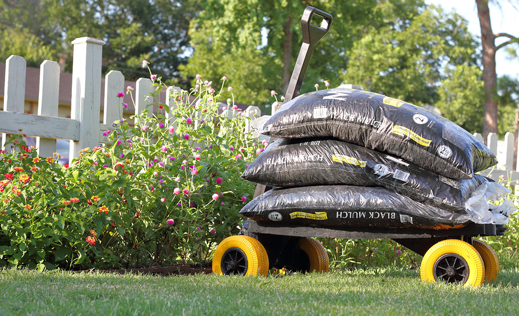 Bags of mulch in front of a garden