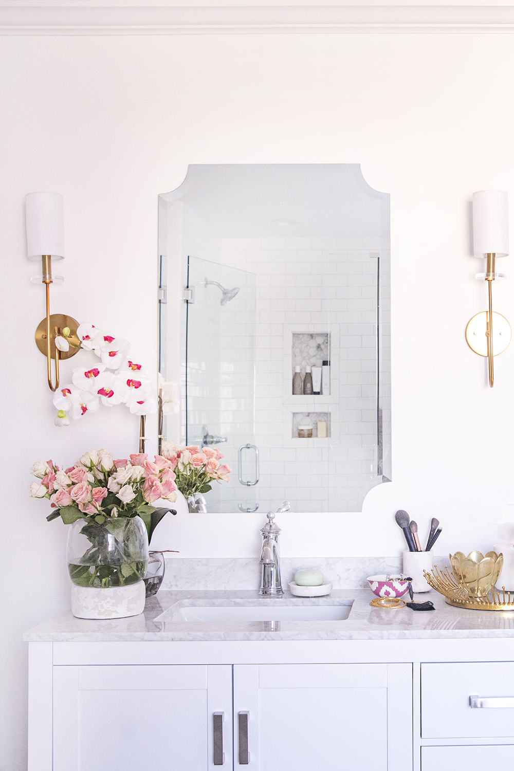 A large mirror and two sconces hang over a white vanity with a white top.