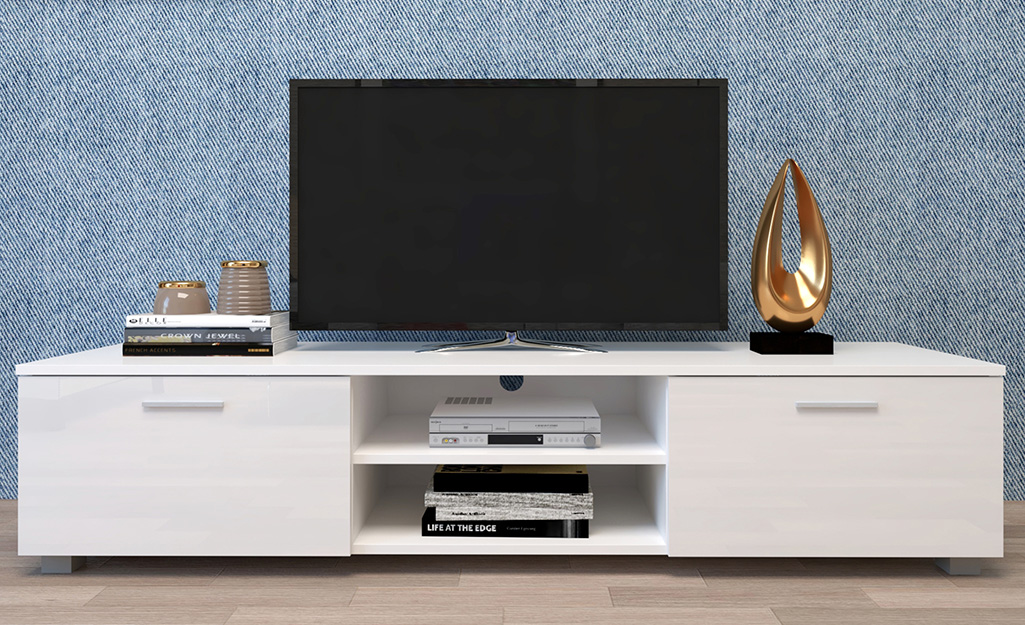 Blue wallpaper behind a white low-profile media cabinet.
