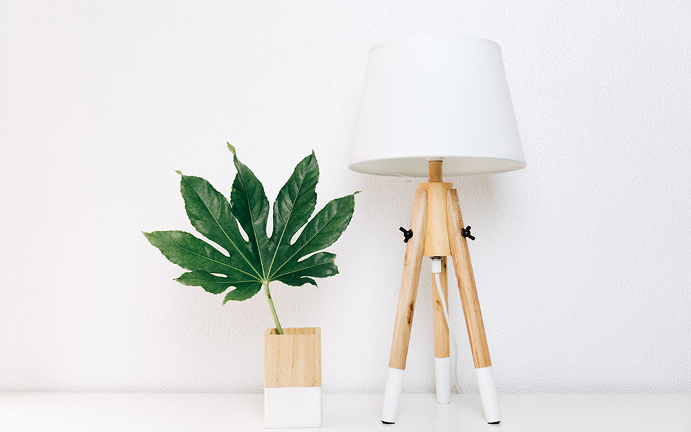 A white and brown wood table lamp and matching vase stand side by side on a tabletop.