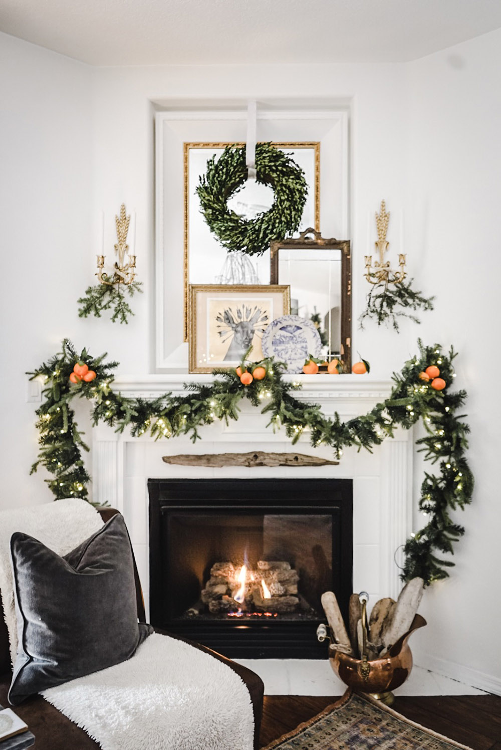 A wreath and garland hang above a burning fireplace.