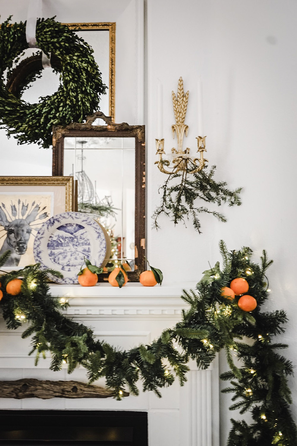 A fireplace mantel draped with garland and oranges.