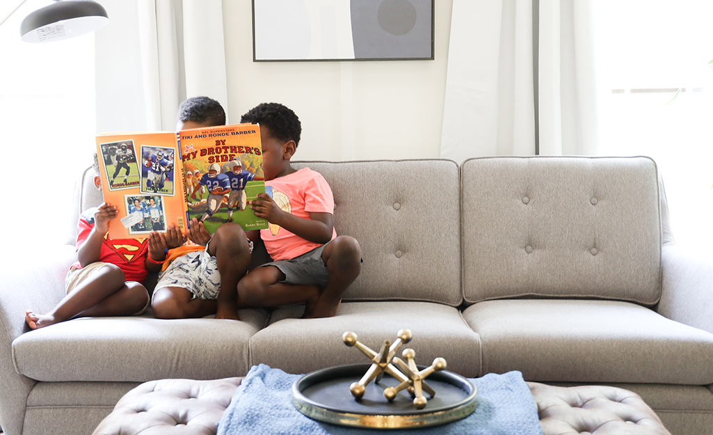 A comfy couch where two children sit reading together.
