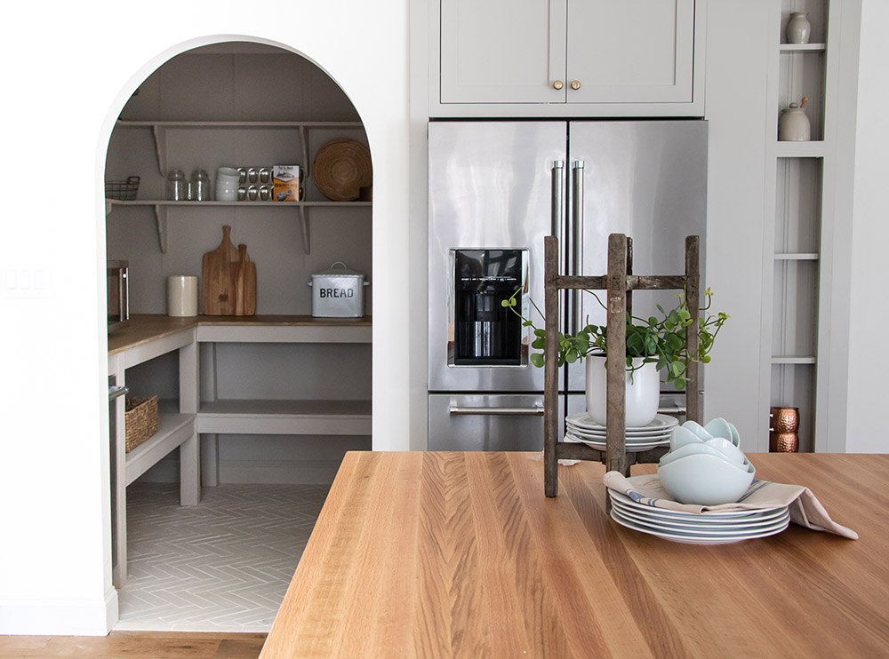 A kitchen with a stainless steel refrigerator and open pantry.
