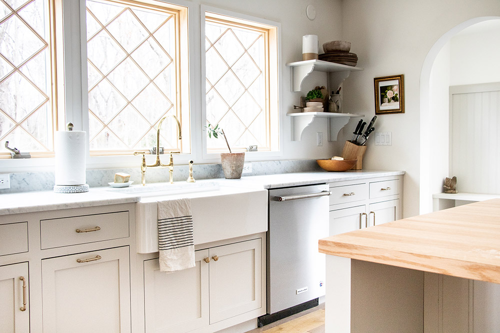 A white kitchen with white lower cabinets and open white shelves.
