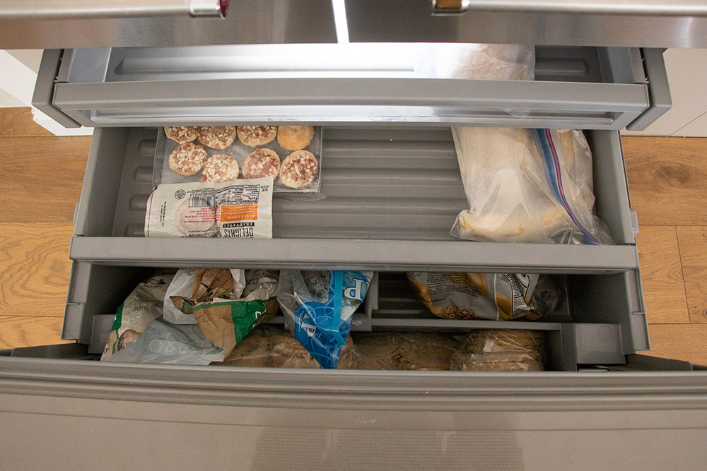 A KitchenAid refrigerator with an opened bottom freezer.