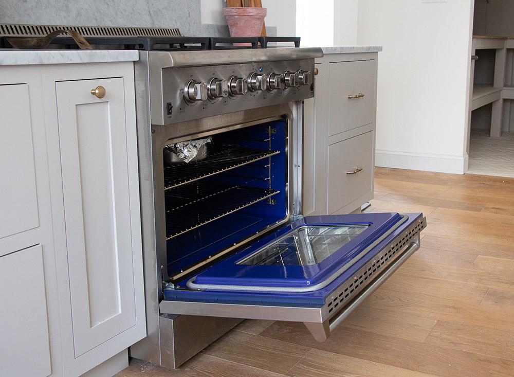 A stainless steel gas range and oven with a blue interior.