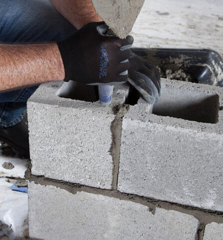 Construction Worker Applying Mortar to Cinderblocks