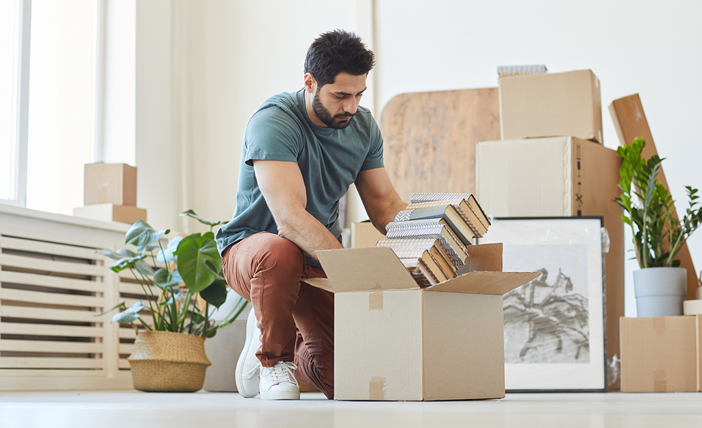 A young man putting books into moving boxes.