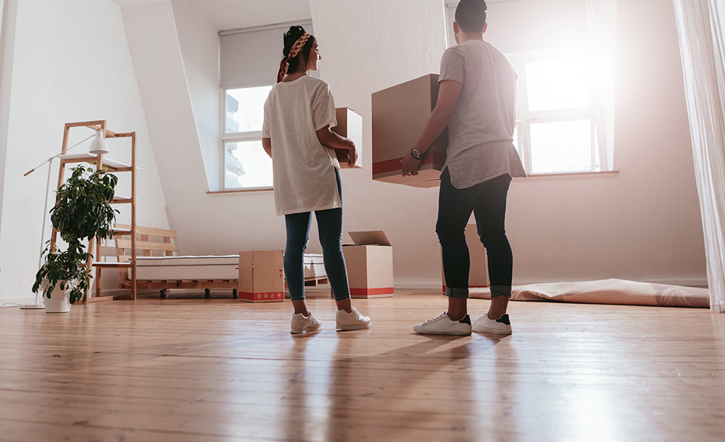 People carrying the last remaining moving boxes from a room.