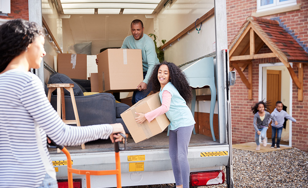 A group of people unloading a moving truck in front of a house. A group of people unloading a moving truck in front of a house.