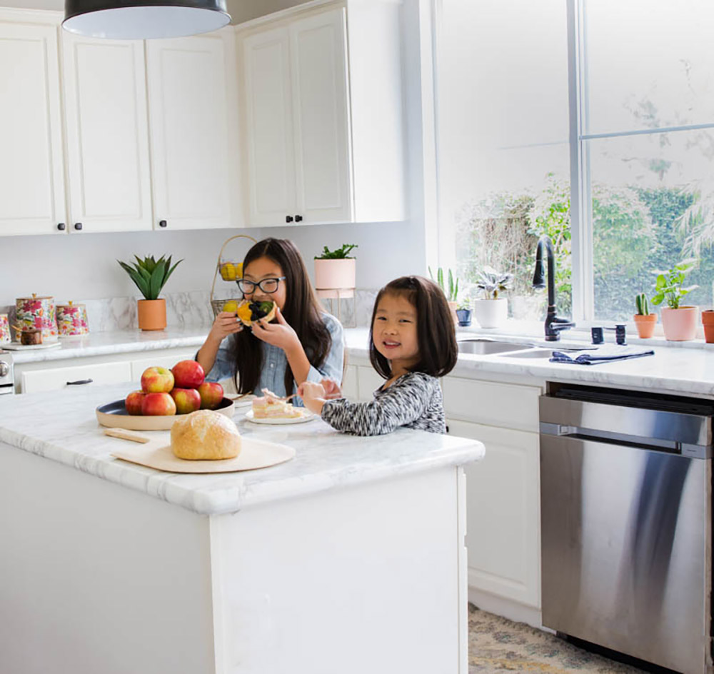 Two children standing behind a kitchen island in front of a window. Two children standing behind a kitchen island in front of a window.