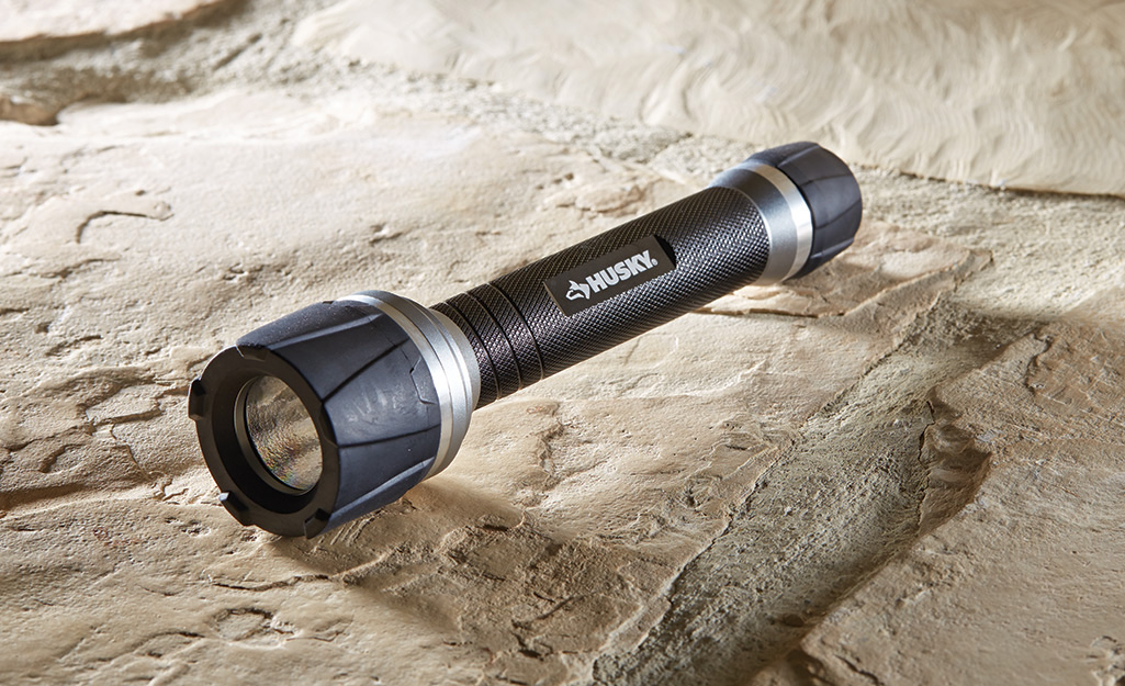 A black flashlight sits on a rock.