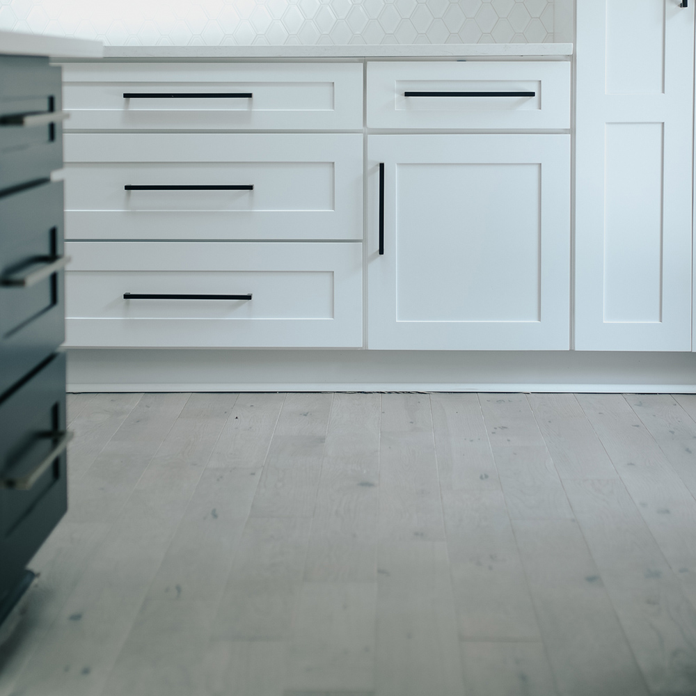 A room with hardwood flooring and white cabinets with black hardware. A room with hardwood flooring and white cabinets with black hardware.